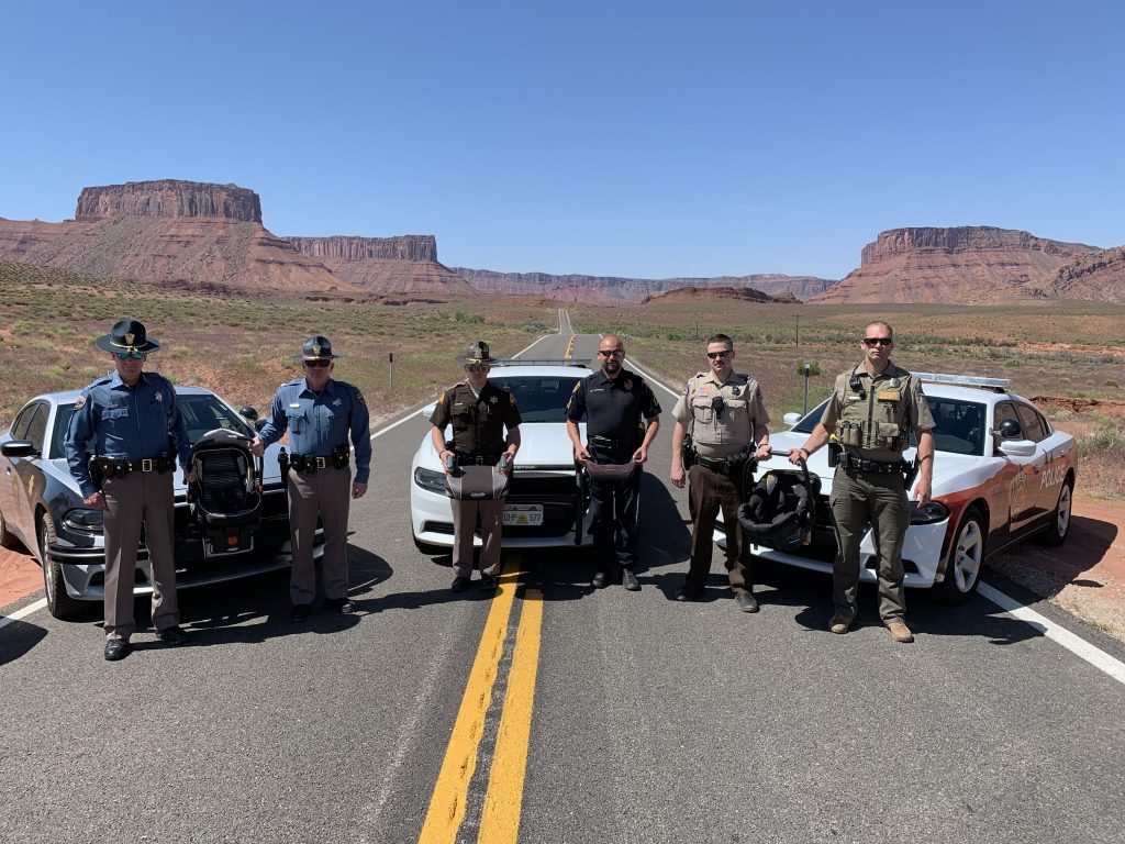 Grand County Sheriff, Colorado State Patrol, UHP, Moab City Police and San Juan County Sheriff stand by their vehicles with Monument Valley in the background