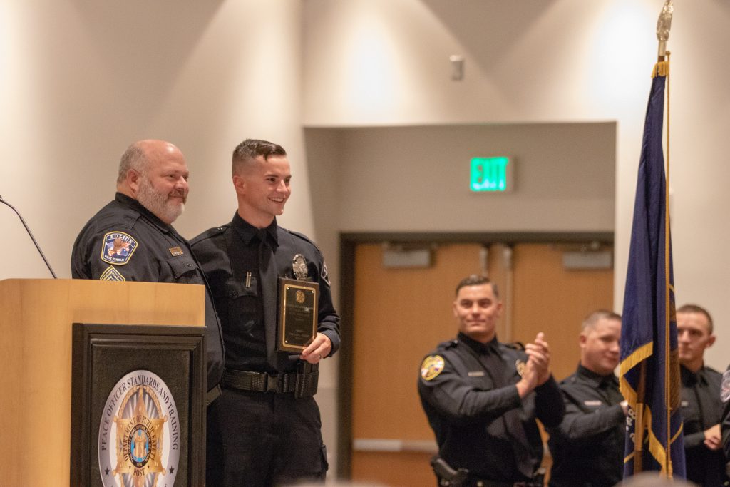 Enoch City PD Officer Mackelprang accepts the award for outstanding achiever. He appears onstage with a representative from the UPOA and holds the award.