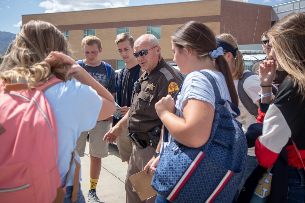 Trooper Bradford stands at the center of a circle of the student body officers and briefs them about the plans for distributing the Creamies.