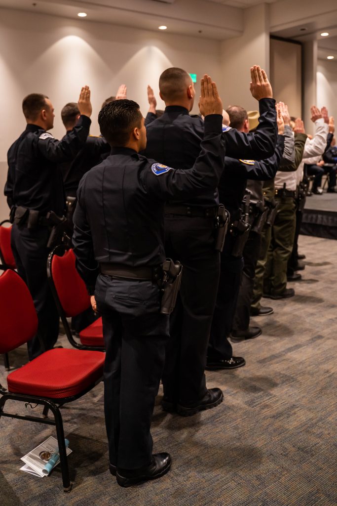 Officers stand with their right hands raised as they take the law enforcement code of ethics.