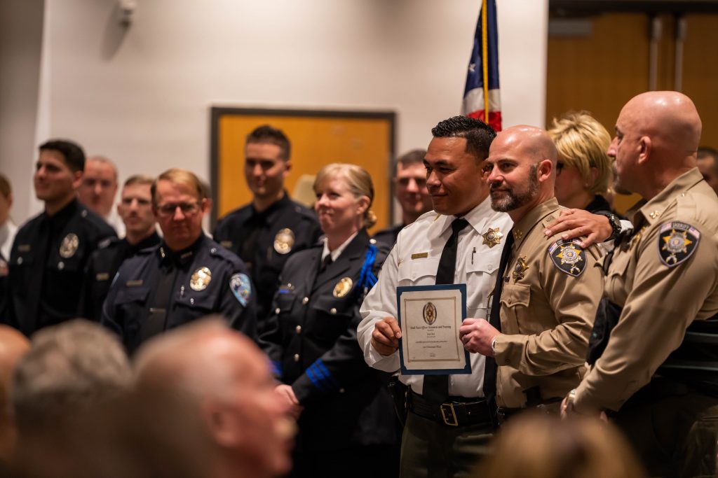 New officer poses with members of his new department with his law enforcement certificate for a photo.