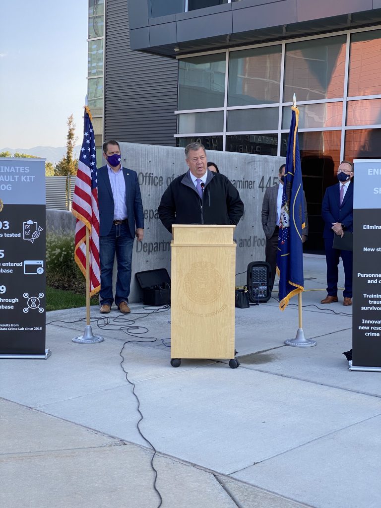 State Representative Eric Hutchings speaks at the podium at the press conference marking the elimination of Utah's sexual assault kit backlog.
