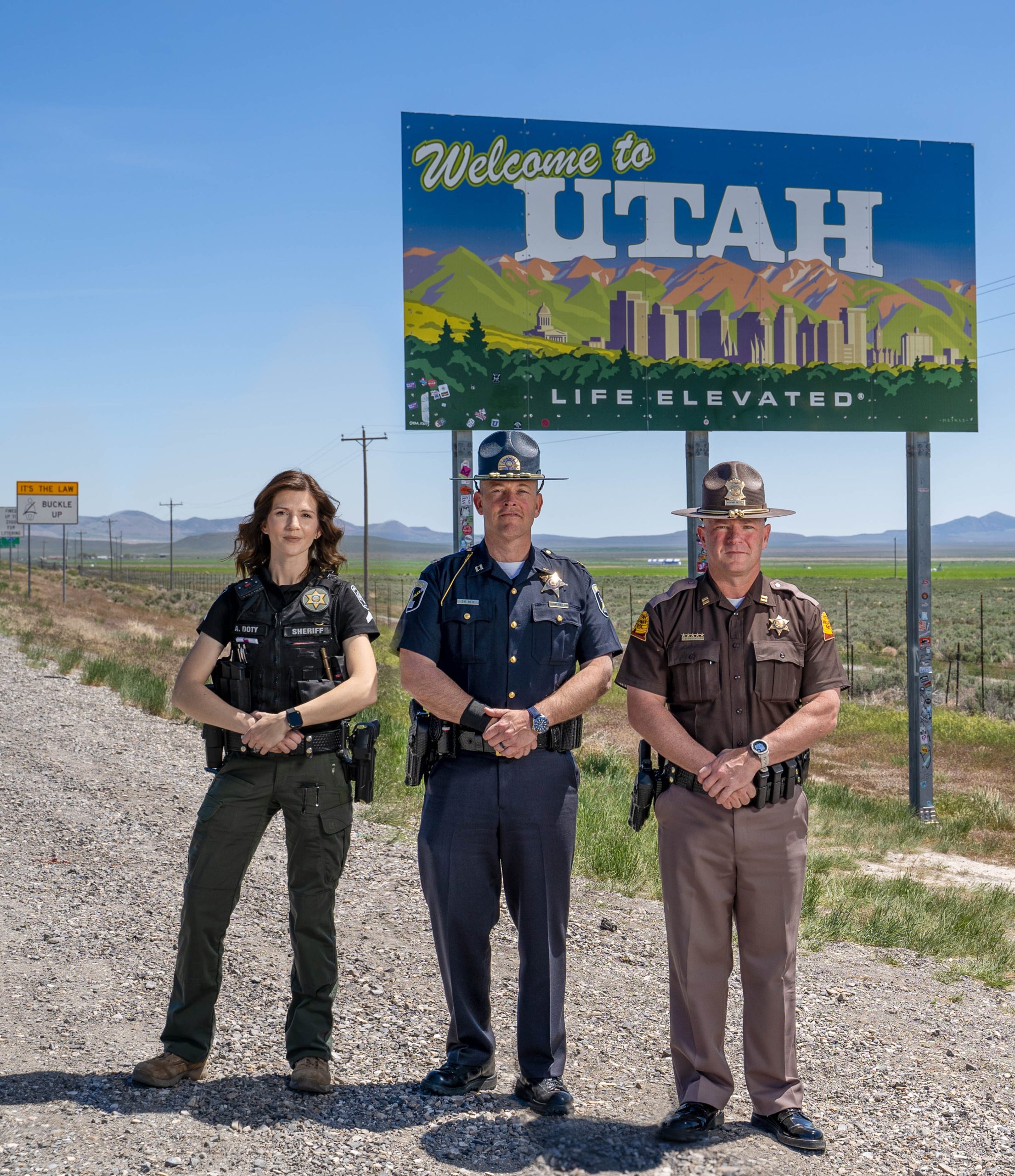 A Cassia County Deputy, ISP Captain and UHP Captain stand by the Welcome to Utah sign.